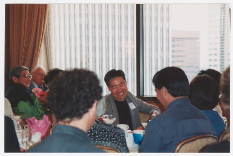 Tom Ikeda sitting and smiling at Humanities Washington (ddr-densho-506-29)