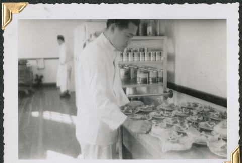 Man standing in kitchen making salads (ddr-densho-434-284)