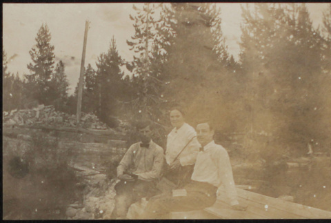 Two men and a woman sitting on a log (ddr-densho-355-659)