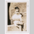 Photo of a toddler sitting and holding a lunch pail (ddr-densho-483-746)