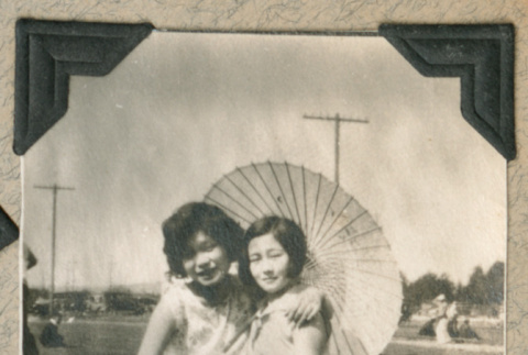 Two women sitting in field with parasol (ddr-densho-383-53)