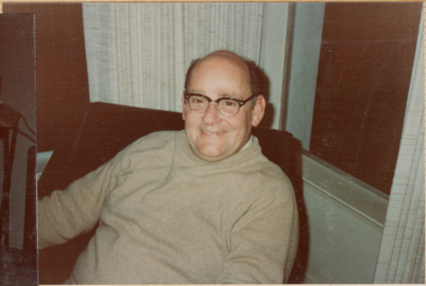 Man seated in chair smiling at camera (ddr-densho-426-2228)
