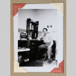 Man in military uniform sits at a small desk (ddr-densho-404-394)