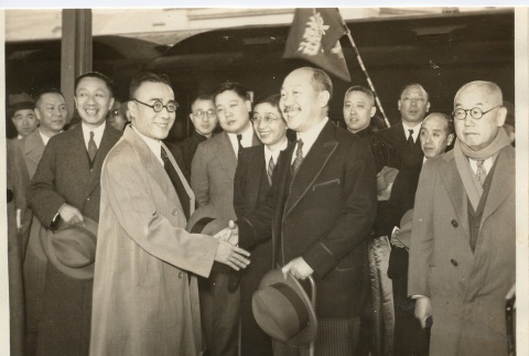 Two men shaking hands in front of a group (ddr-njpa-1-1741)