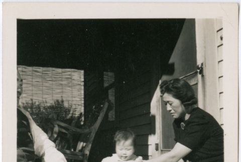 Sally Domoto tending to infant on porch (ddr-densho-329-772)