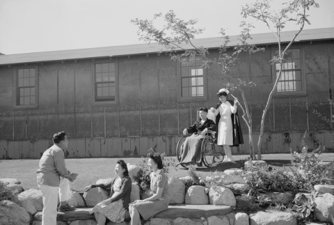 Nurse with patient and others outside barracks (ddr-densho-93-3)