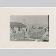 Photograph of Manzanar staff housing with a rock fence and a car in front (ddr-csujad-47-352)