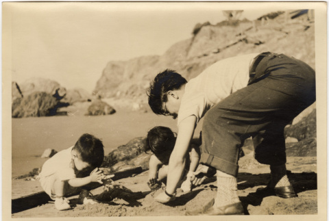 Man and two children playing on a beach (ddr-densho-426-43)