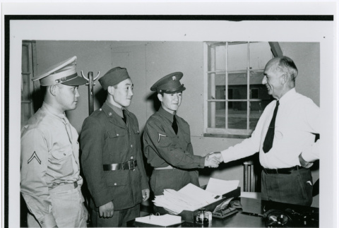 Three Japanese Men Standing in Front of Desk at Hart (sic) Mountain Relocation Camp, c. 1941 (ddr-densho-122-738)