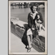 Woman holding dog sitting on wall by river (ddr-densho-466-114)