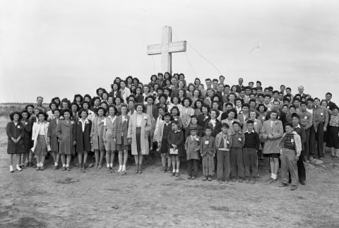 Group gathered in front of an outdoor cross in camp (ddr-fom-1-100)
