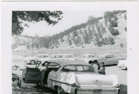 Car in parking lot, Tomoye (Nozawa) Takahashi standing on one side (ddr-densho-426-2203)