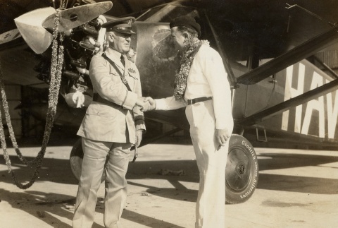 Two men shaking hands in front of an airplane (ddr-njpa-1-2338)