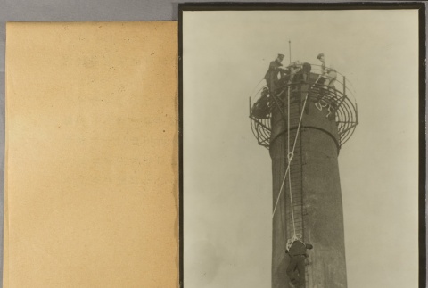 A man climbing a factory smokestack while men above hold a safety rope (ddr-njpa-13-1462)