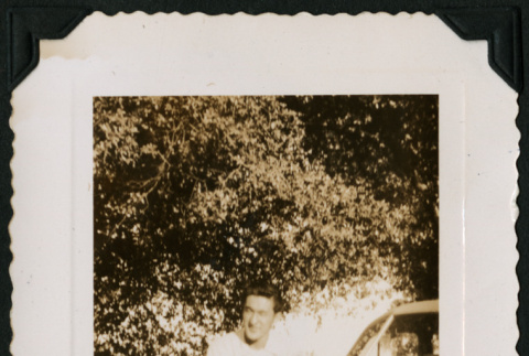 Walter Matsuoka sits on the fender of a car (ddr-densho-390-82)