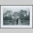 Two men standing by pillar and pond (ddr-densho-293-182)