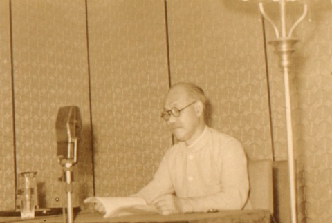 Man seated behind microphone (ddr-njpa-4-240)