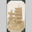 Man standing next to stone lantern and temple (ddr-ajah-2-721)
