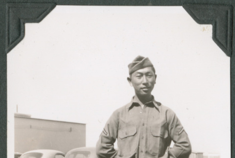 Joe Iwataki in uniform standing on road near cars (ddr-ajah-2-154)