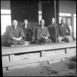 Group of men seated outside house (ddr-densho-426-307)