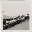 Group sitting on bench at overlook with Oakland Bay Bridge in background (ddr-densho-426-955)