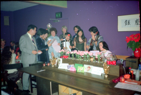 Group standing around piano, singing (ddr-densho-426-603)