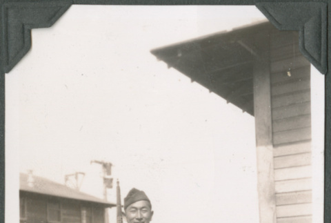Joe Iwataki standing with rifle outside building (ddr-ajah-2-68)