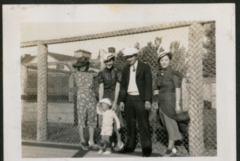 Adults and one child pose in front of fence (ddr-densho-359-951)