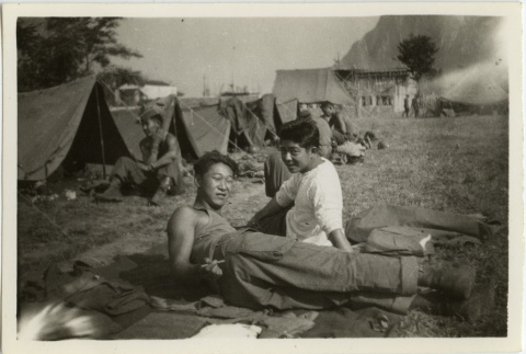 Soldiers lounging on the ground outside tents (ddr-densho-201-186)