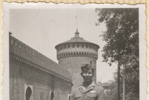 Man standing outside brick building with tower (ddr-densho-466-396)
