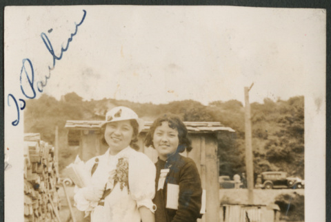 Two women by lumber pile and shed (ddr-densho-316-305)