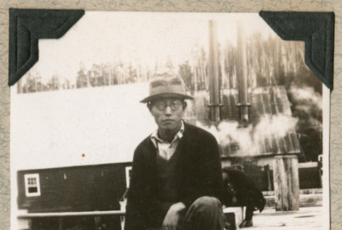 Isamu Ito sitting along edge of boardwalk (ddr-densho-383-254)