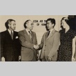 Two men shaking hands, posing with a woman and another man (ddr-njpa-2-948)