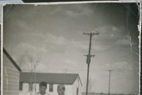 Two men walking on road by barracks (ddr-densho-493-105)