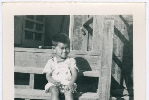 Boy sitting on barracks steps in Minidoka (ddr-densho-543-5)