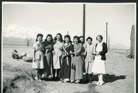 Photograph of eight women standing outside next to a barracks with the Sierra Nevada in the background (ddr-csujad-47-186)