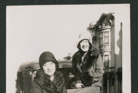 two women sitting on the hood of a car (ddr-densho-378-764)