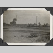 View of tents behind fence and guard tower (ddr-densho-466-665)
