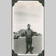Man in uniform standing in road with barracks in background (ddr-ajah-2-80)