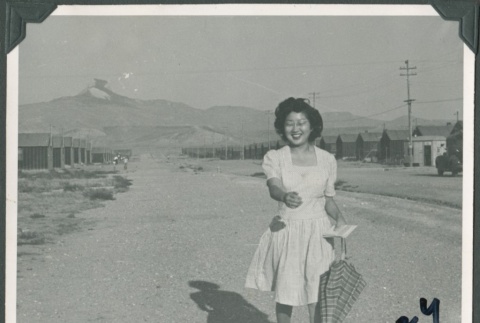 Woman walking with umbrella at Heart Mountain concentration camp (ddr-densho-321-118)
