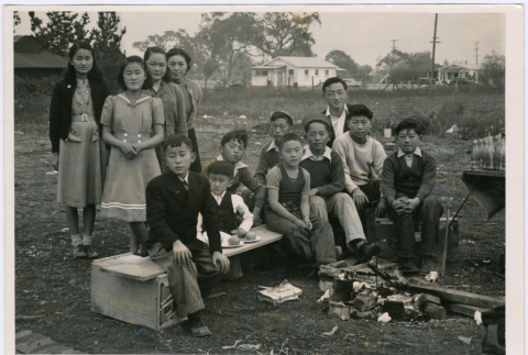 Thirteen adults and children around campfire on Okamura farm (ddr-densho-458-31)
