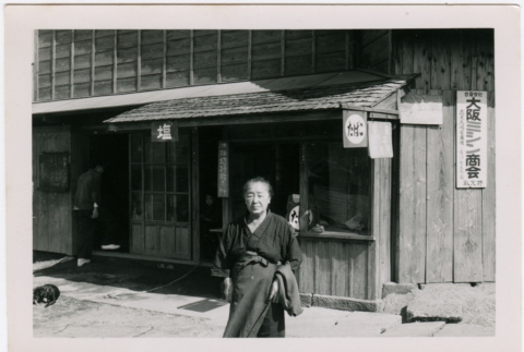 Elderly woman stands in front of building (ddr-densho-348-14)