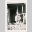 Girl standing in doorway of barracks (ddr-densho-329-1321)