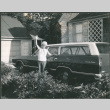 Agnes Sakura waving next to station wagon (ddr-densho-523-606)