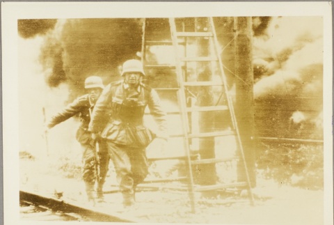 Two German soldiers walking away from an explosion (ddr-njpa-13-909)