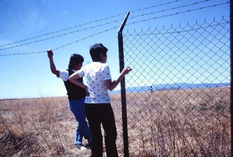 Two pilgrims standing next to a barbed wire fence at Tule Lake (ddr-densho-294-50)