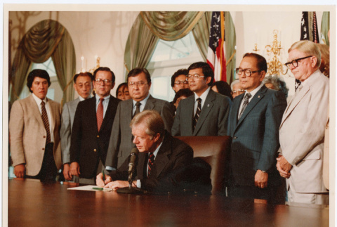 Men standing behind President Jimmy Carter in White House, signing of Commission of Wartime Relocation and Internment of Citizens Act into law (ddr-densho-393-5)