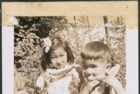 Three children eating watermelon (ddr-densho-483-1079)