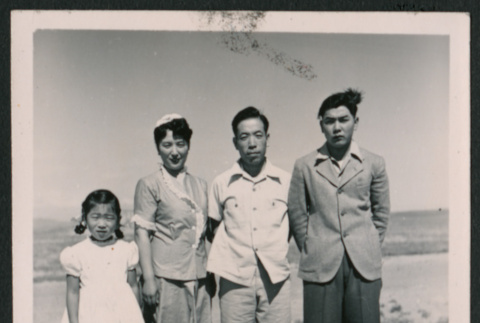Group photo of two men, one woman, and a young girl in an open field (ddr-densho-362-36)