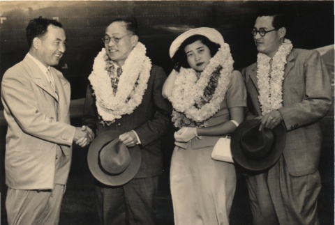 Two men shaking hands, posing with a woman and another man (ddr-njpa-4-4)